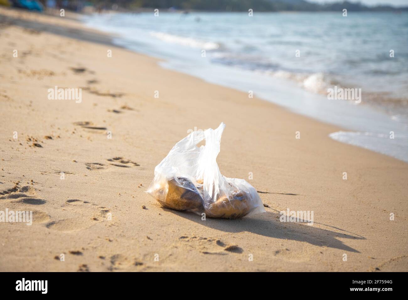 plastic bag lying on a sandy tropical beach. environmental pollution. trash in the sea Stock Photo