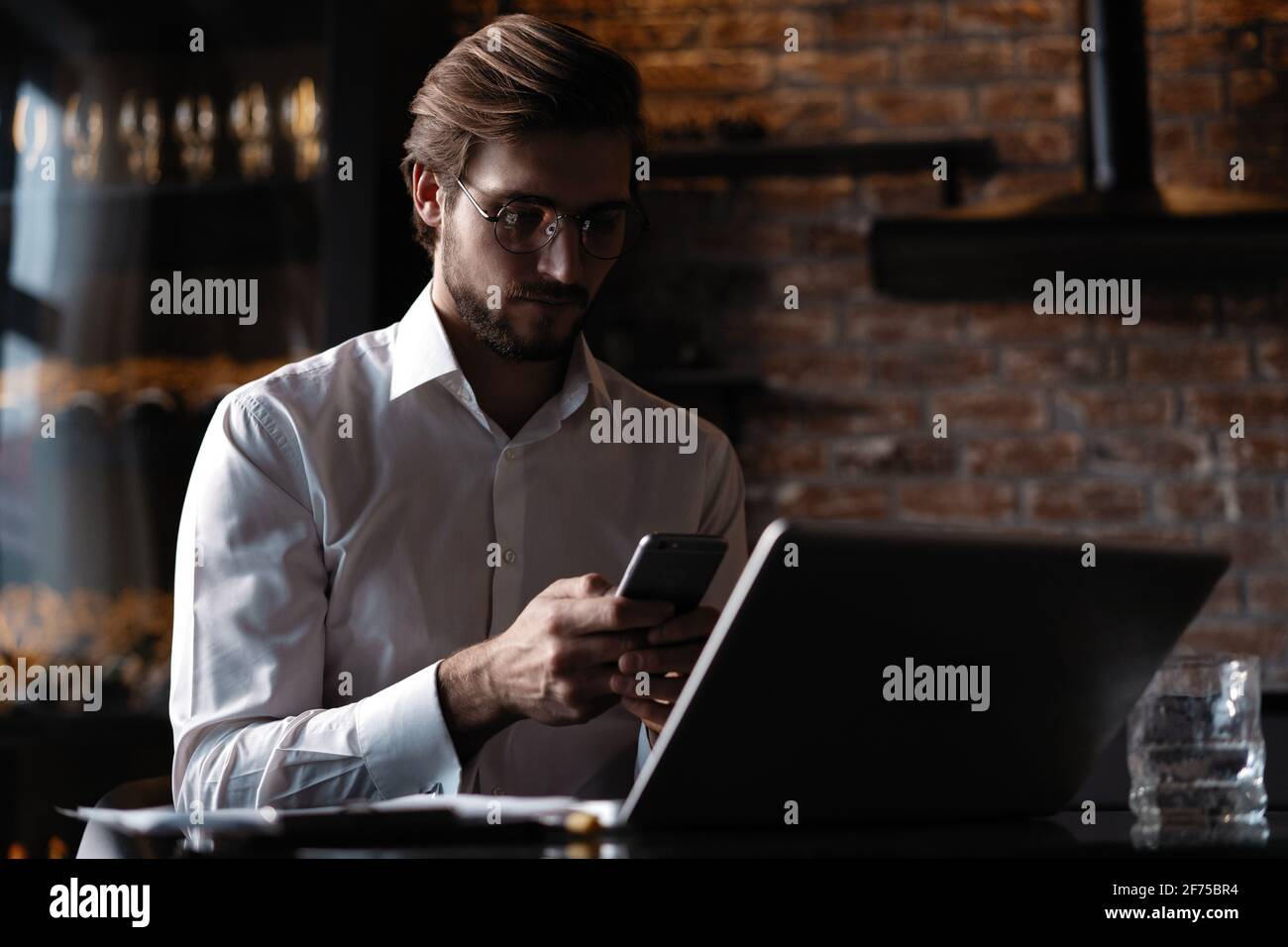 Casual man relaxed using smart phone, young man browsing on smart phone in cafe interior. Stock Photo