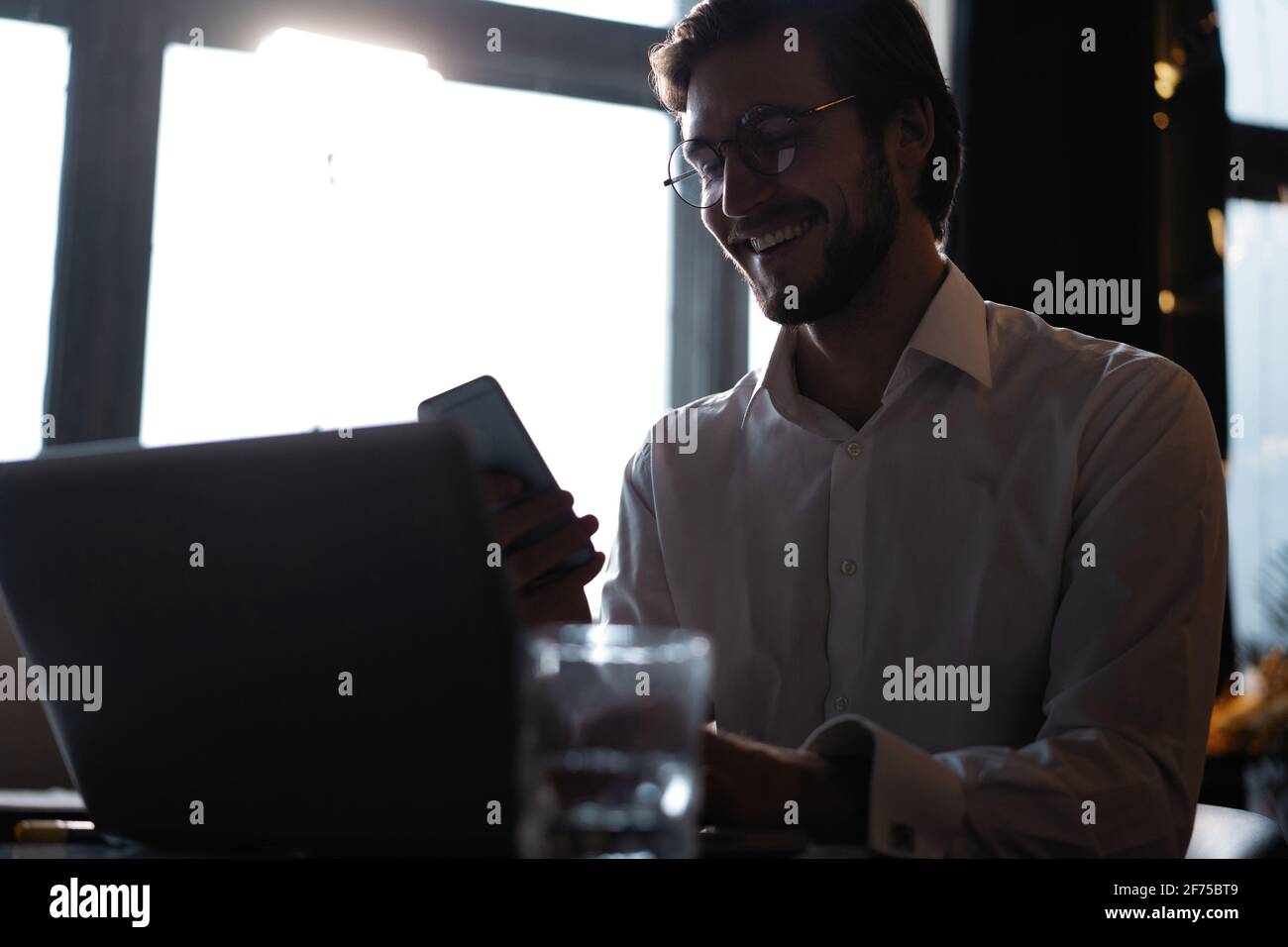 Casual man relaxed using smart phone, young man browsing on smart phone in cafe interior. Stock Photo