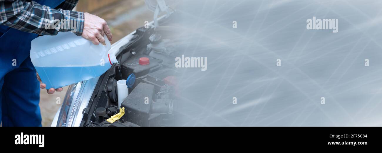 Hands of mechanic pouring blue windshield washer fluid in a car; panoramic banner Stock Photo