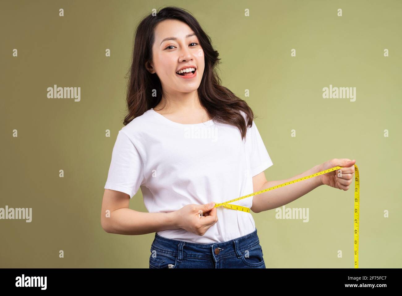 Young asian girl happily holding the tape measure after losing weight ...