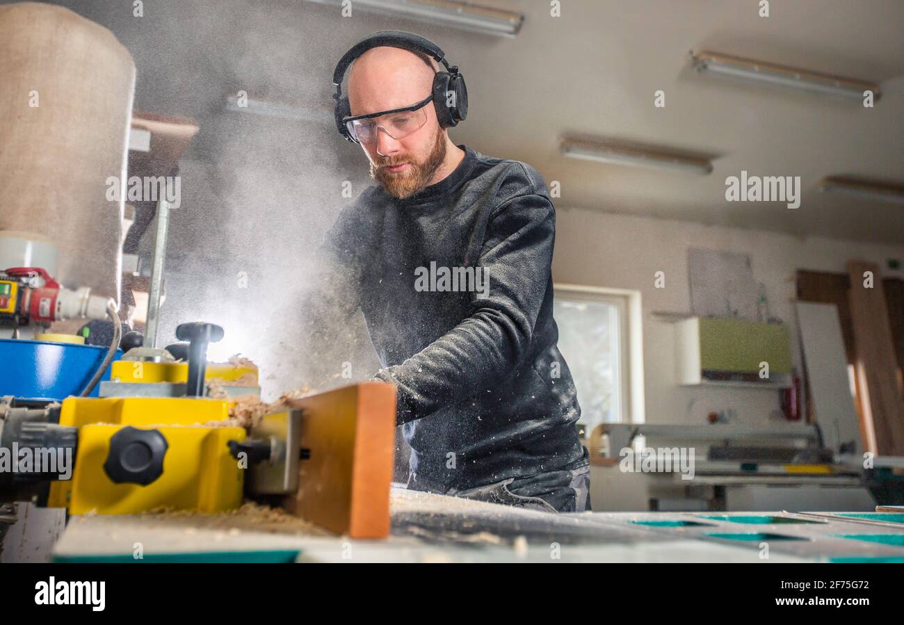 Carpenter working on woodworking saw machines in carpentry shop, industrial concept Stock Photo