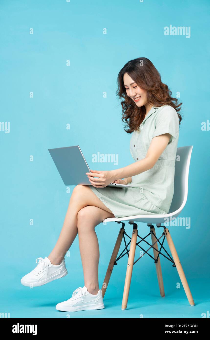 Young Asian girl sitting on a chair using a laptop with a happy ...