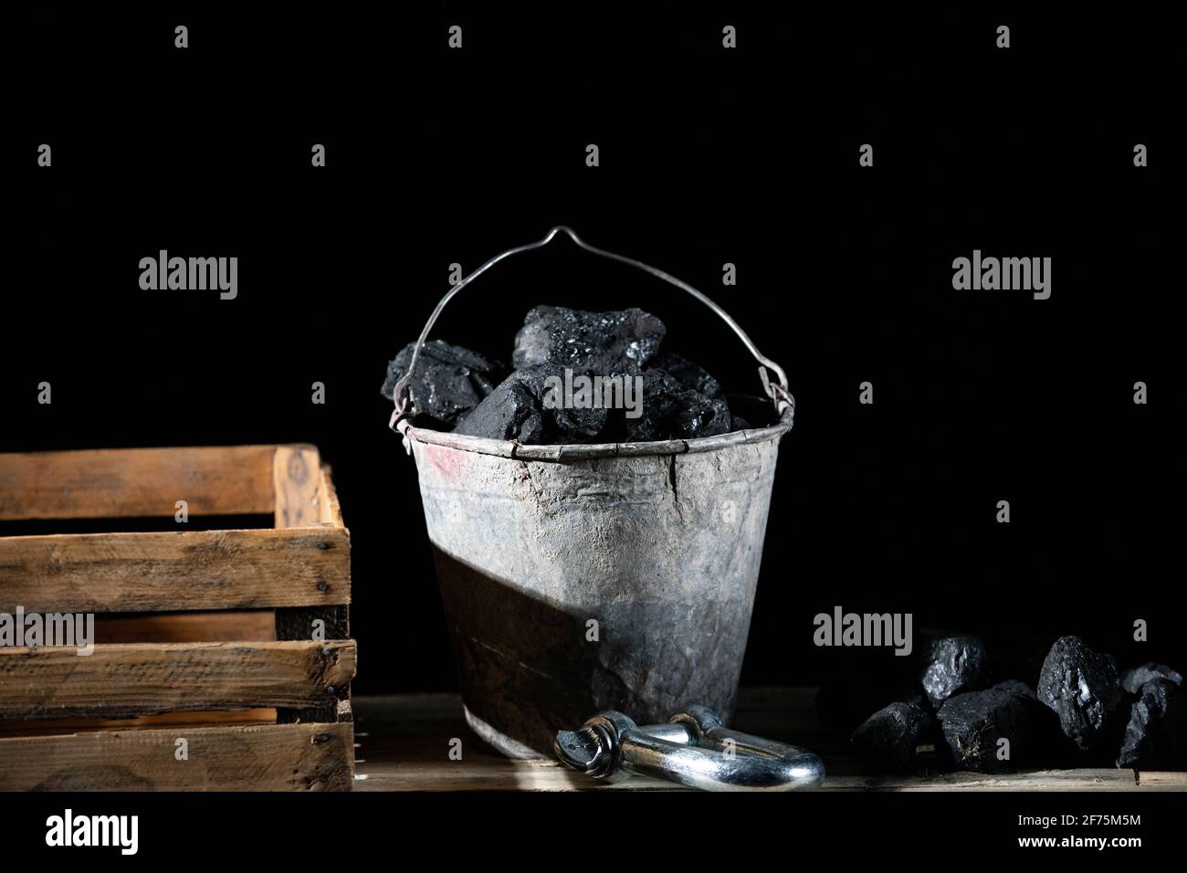 Black bituminous coal lies on a wooden platform and in a galvanized