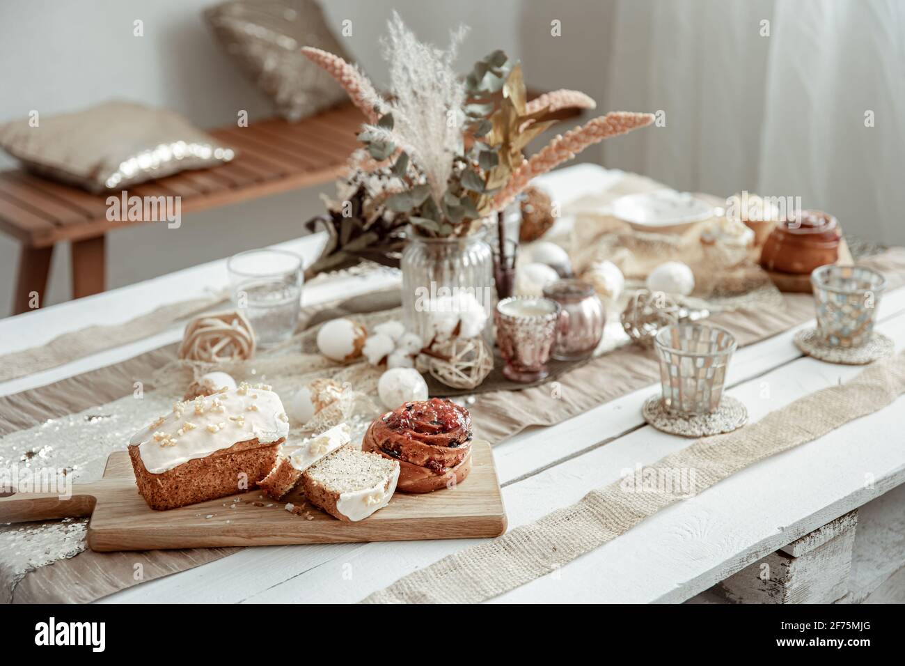 Table with Easter decor elements and festive pastries. Cozy home composition. Stock Photo
