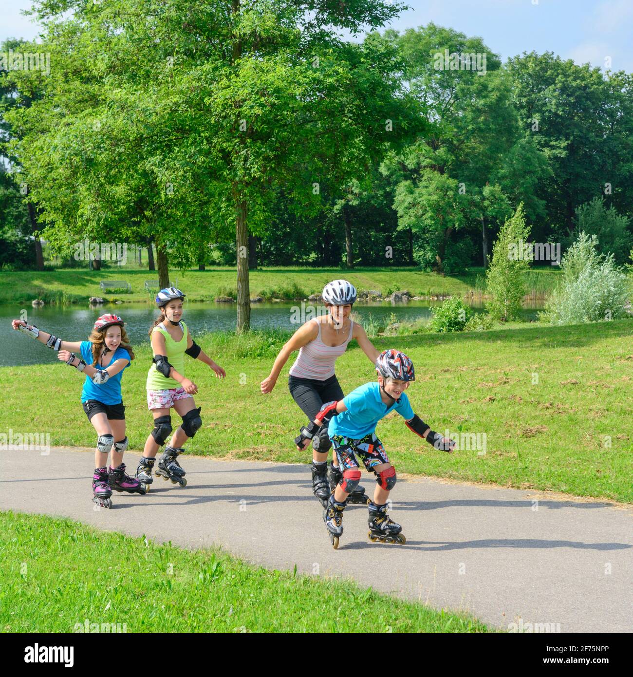Young family doing a tour on inline skates in urban park at a sunny