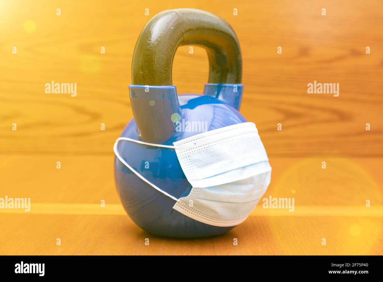 kettlebells on gym with blue surgical mask. Close up. Sports kettlebell in the gym, top view. kettlebell wearing blue medical mask. toned. copy space Stock Photo