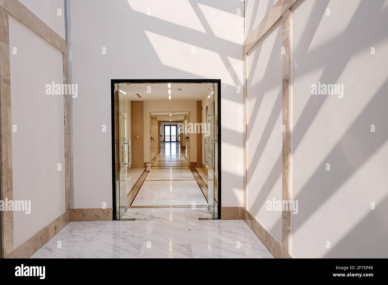 Long empty corridor in light colors with sunlight and shadows. Stock Photo