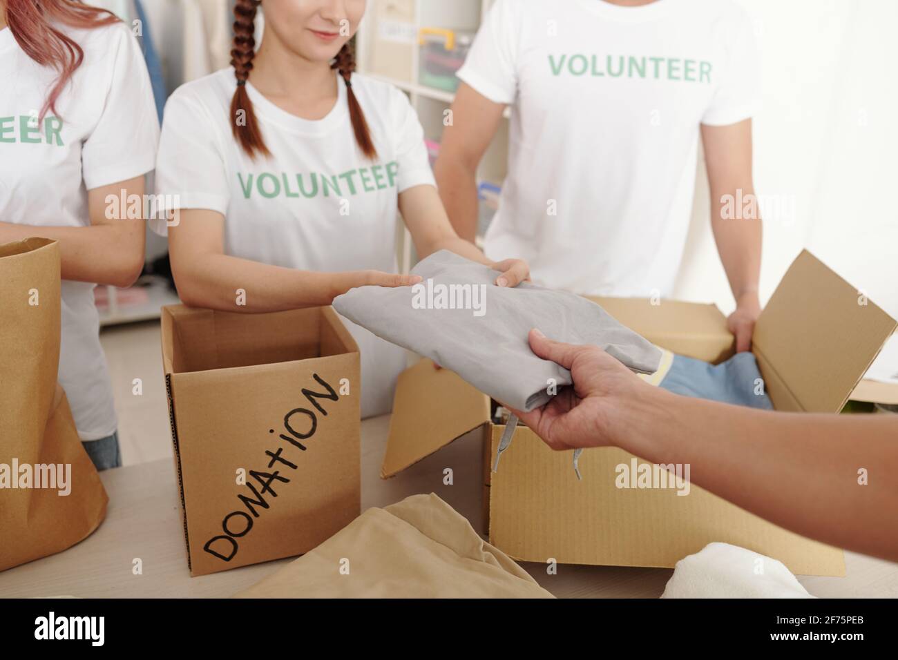 Close-up image of volunteers packing clean clothes for people in need into cardboard donation boxes Stock Photo