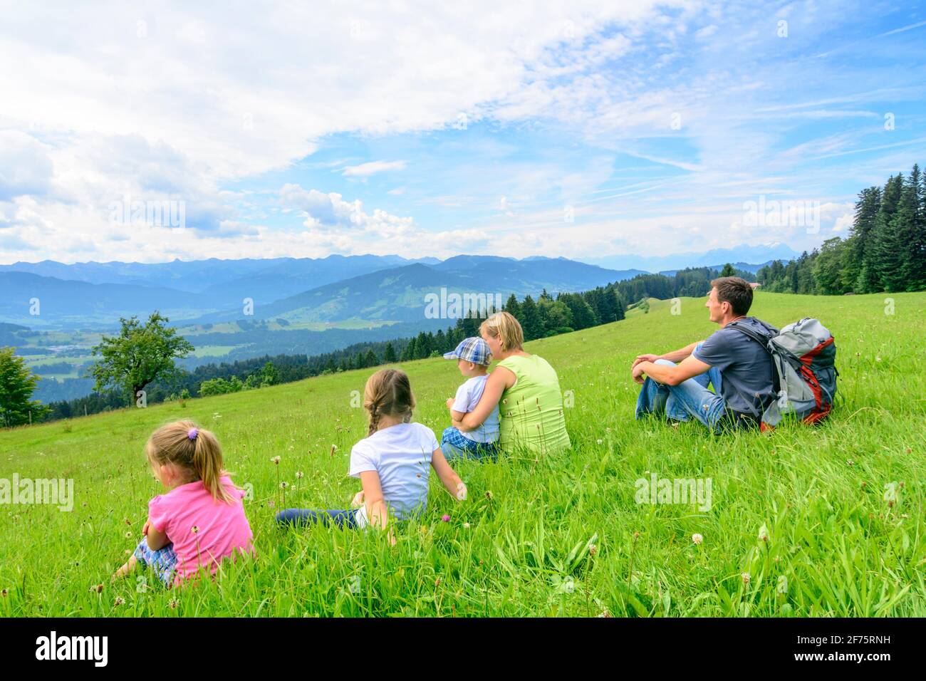 Young family enjoying landscape while sitting on meadow Stock Photo