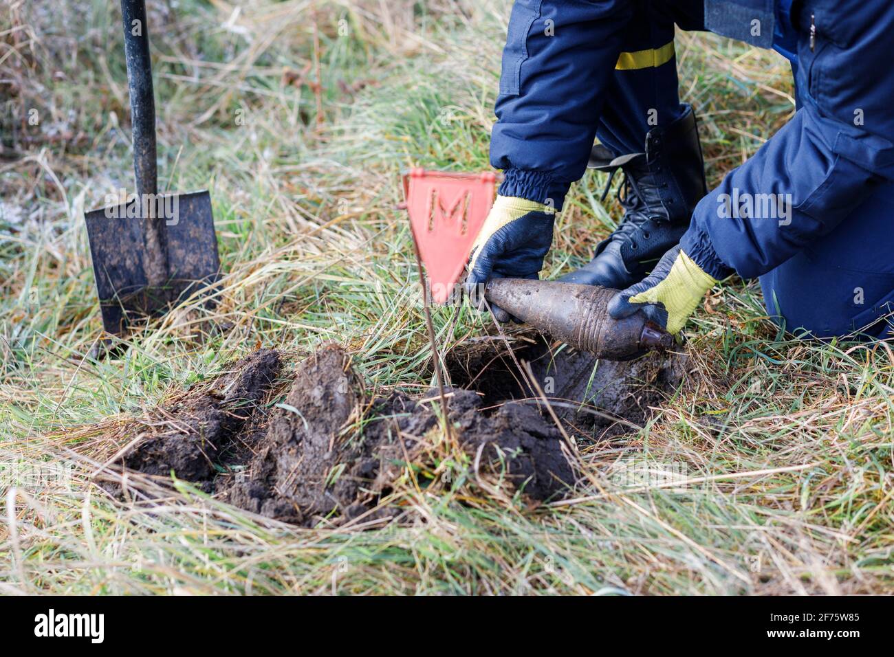 A man in a special suit works with a detector and found an explosive device. Stock Photo