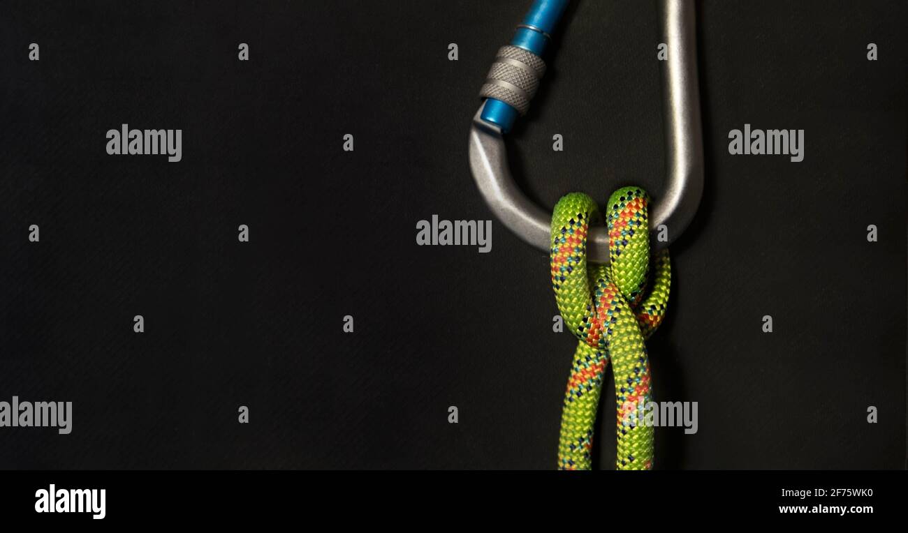Vertical Carabiner with boatman's knot and fluorescent green rope on a black background Stock Photo