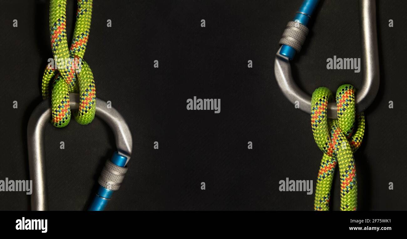 Inverse carabiners with boatman's knot and fluorescent green rope on a black background Stock Photo
