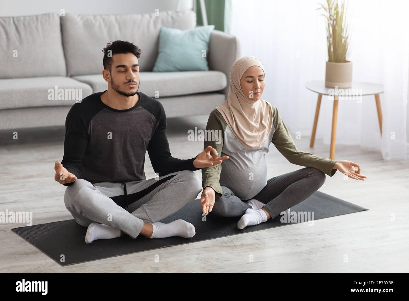 Pregnancy And Yoga. Pregnant Muslim Woman Meditating With Husband