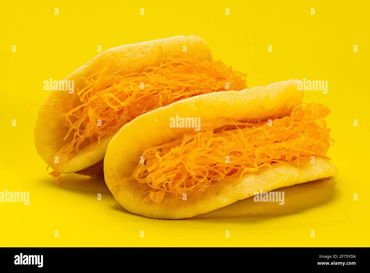 Side view closeup of homemade thick fluffy pancake filling with egg yolk threads on yellow background. Stock Photo