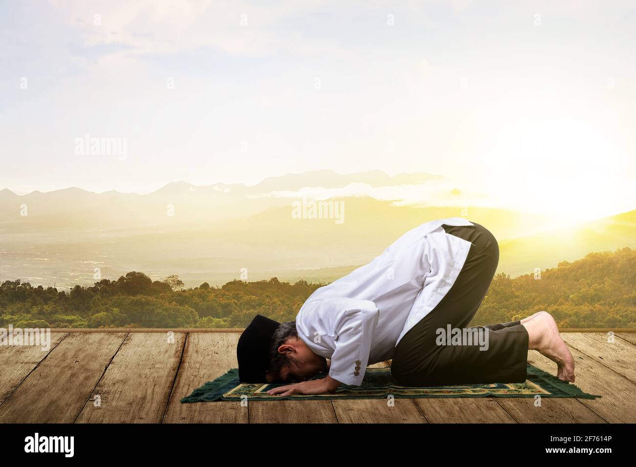 Asian Muslim man in praying position (salat) on prayer rug on the ...