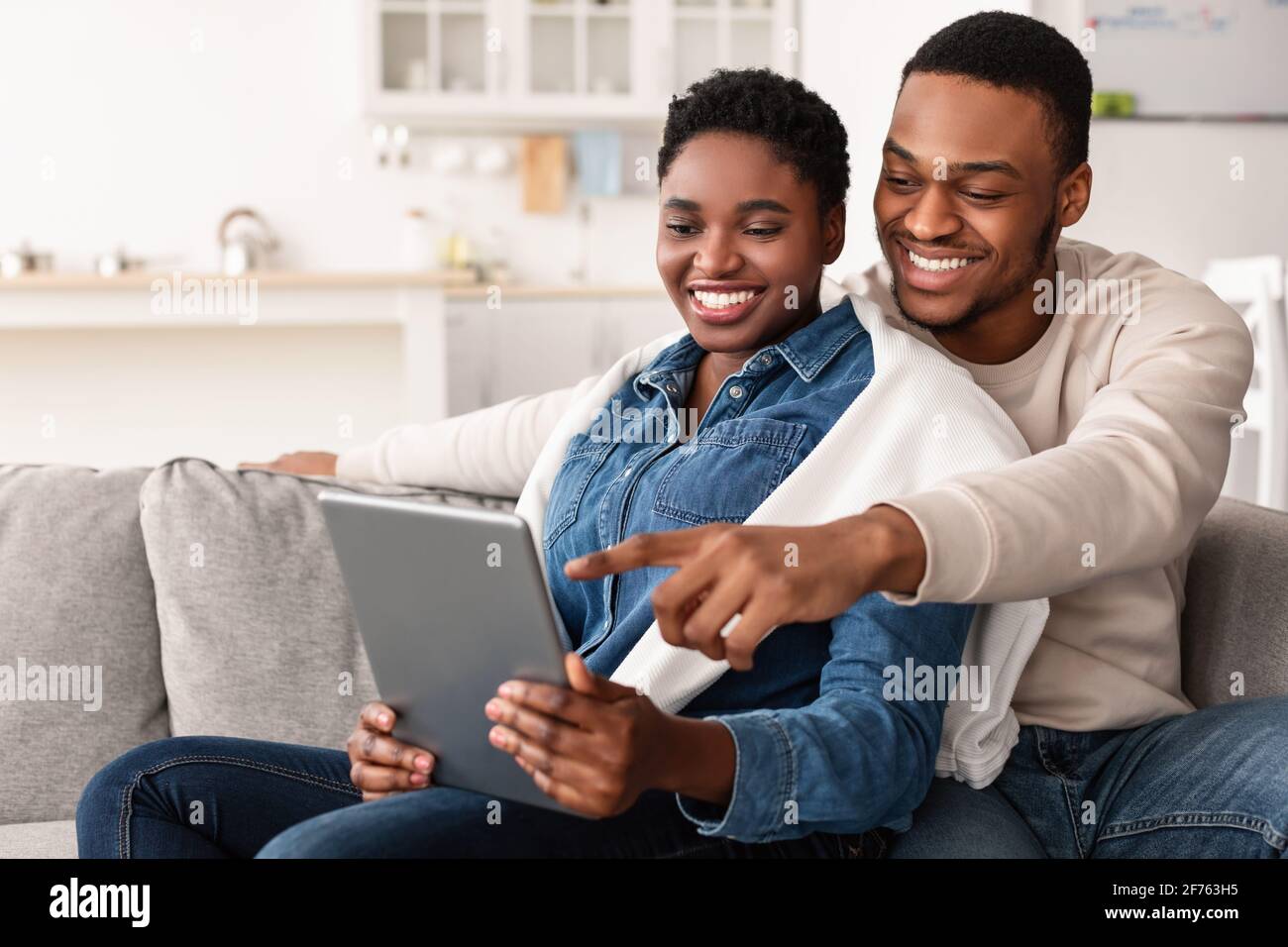African american couple sitting on couch, using tablet Stock Photo - Alamy