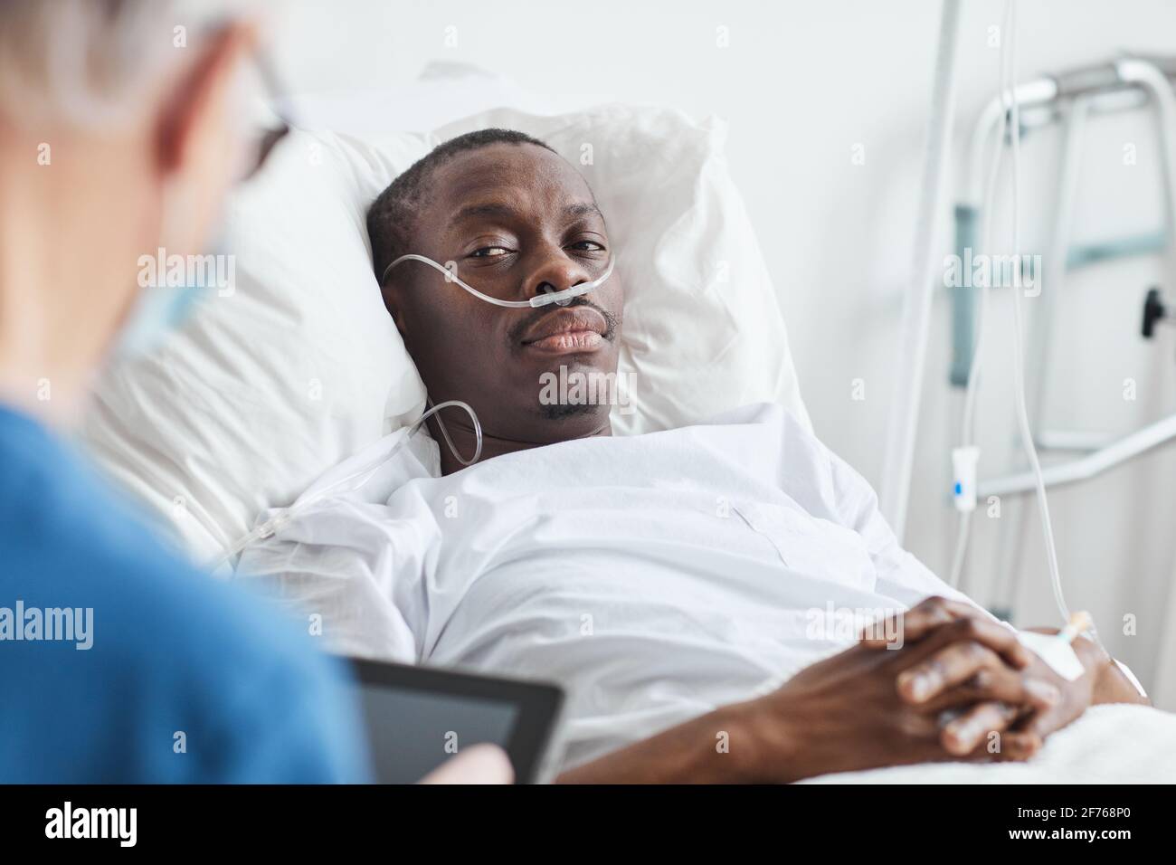 Portrait of AfricanAmerican man lying in hospital bed and looking at