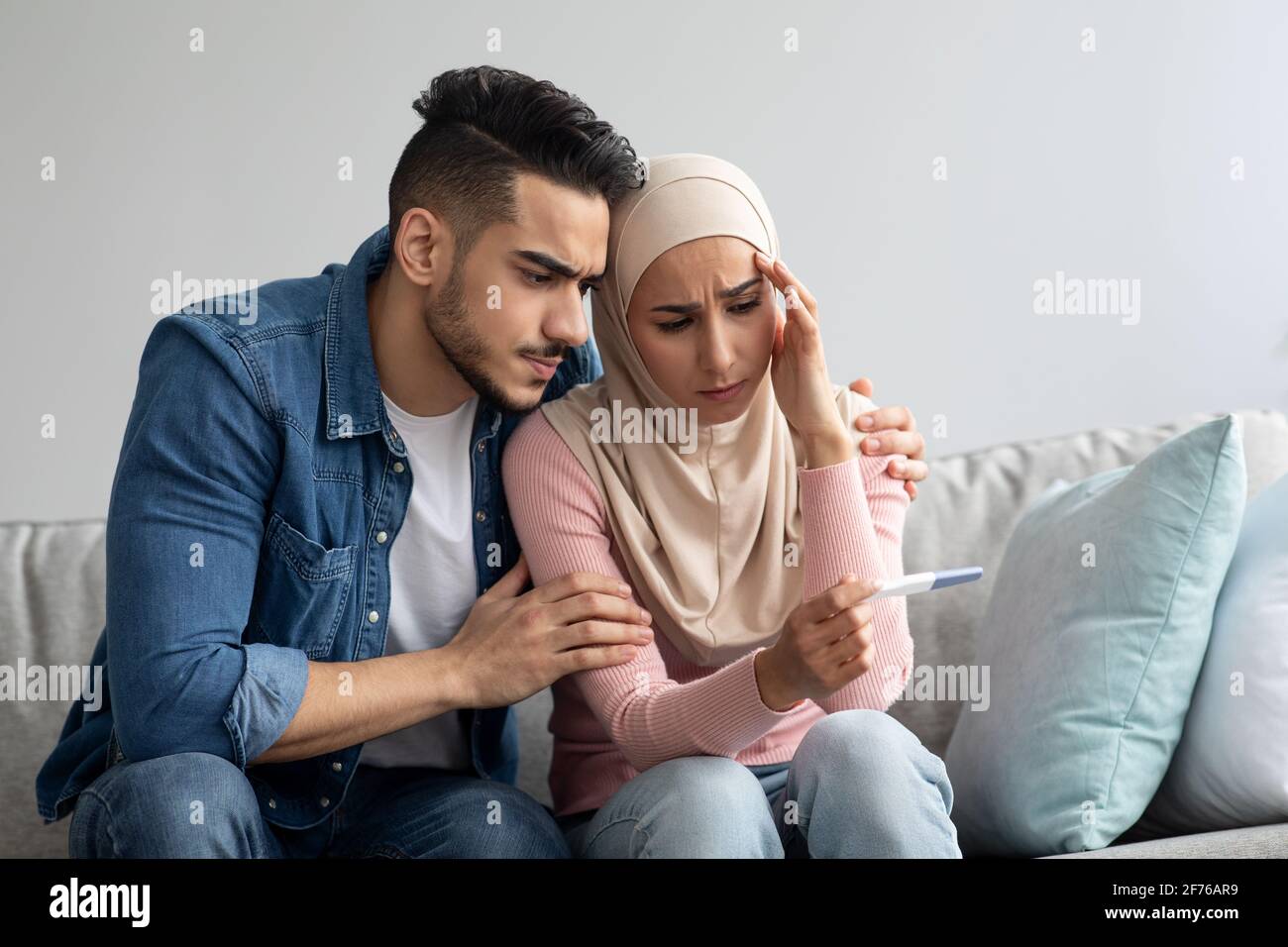 Upset arab couple with negative pregnancy test at home Stock Photo