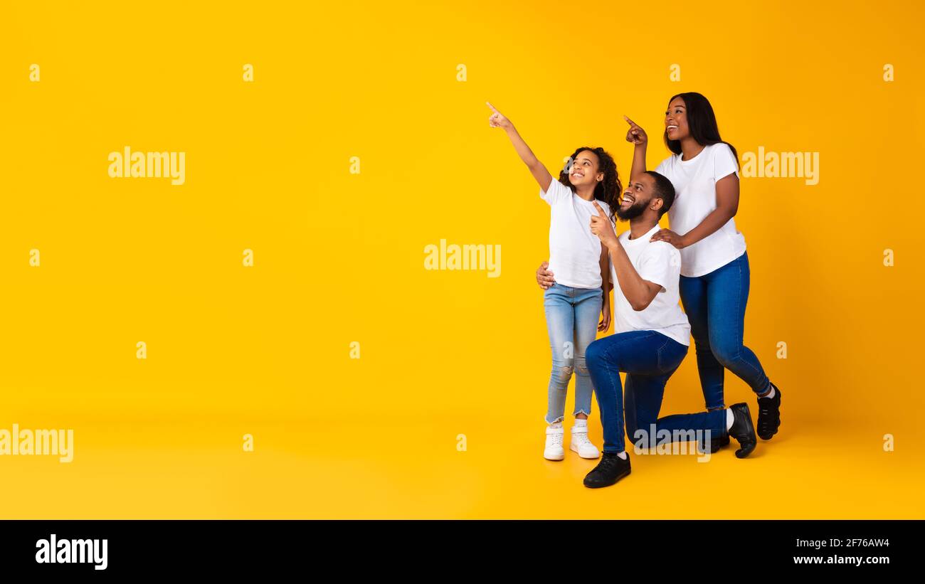 Smiling black family pointing aside at copy space at studio Stock Photo ...