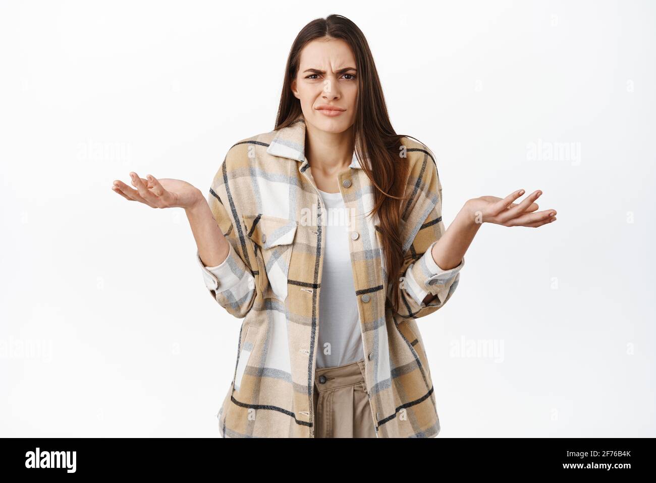 Annoyed and confused woman cant understand wtf happening, shrugging shoulders and grimacing at something ridiculous and stupid, dont know nothing Stock Photo