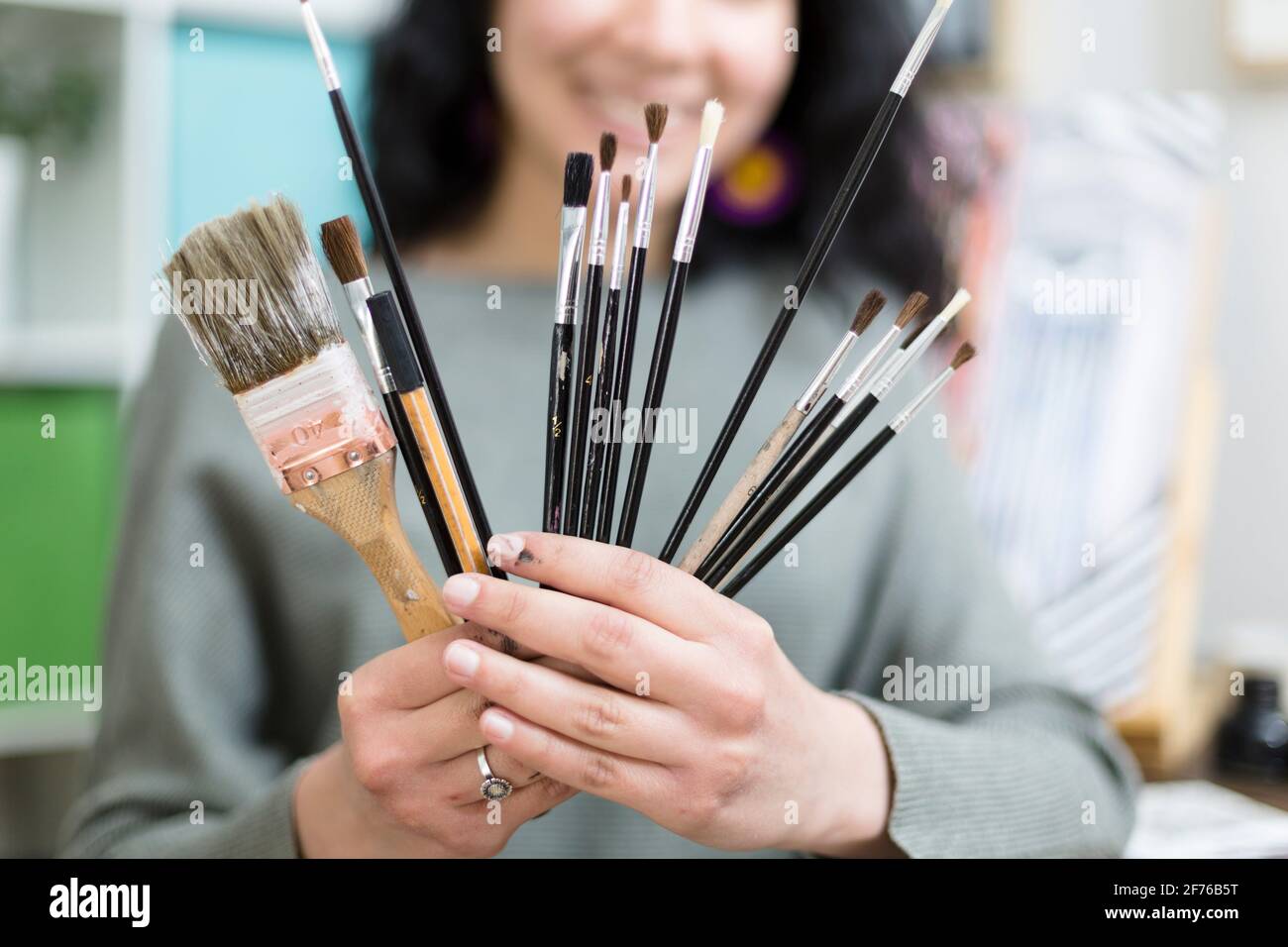Close up of unrecognizable artist showing different types of brushes. Selective focus. Stock Photo
