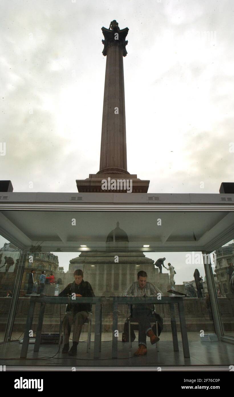 TWO PERFORMERS SIT IN A GLASS BOX READING DATES FROM 998,031BC IN TRAFALGAR SQ.IT IS AN ARTWORK CALLED 'READING 1 MILLION YEARS' BY ON KAWARA.29/3/04 PILSTON Stock Photo