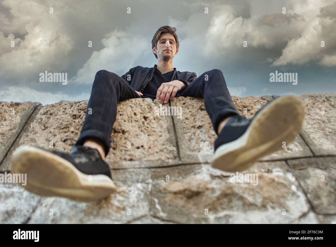 Young Caucasian man sits on pier in Antalya, bottom view. Stock Photo