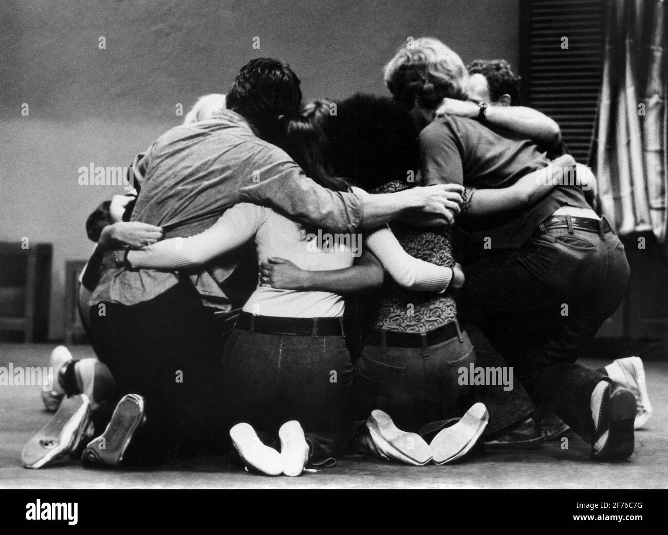 During a local playhouse drama, a group of young people kneels and bonds together during a dramatic moment. Ca. 1970. Stock Photo