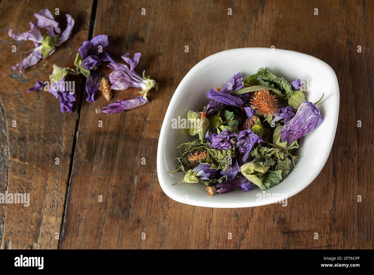 Cough herbal tea in a white bowl - thyme, green anise, ground ivy, pine bud, mallow flowers on a wooden background, top view Stock Photo