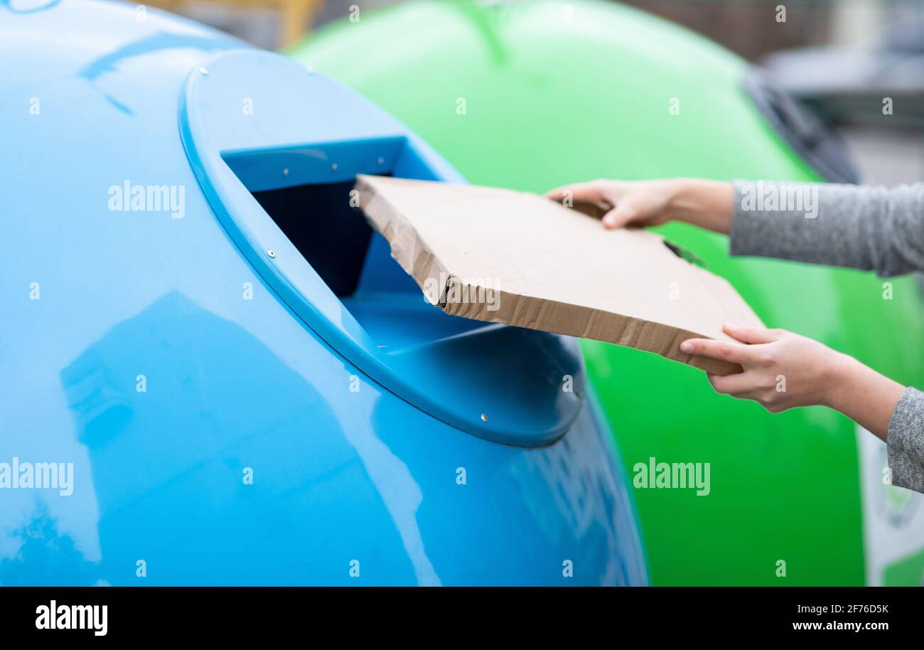 Waste Sorting. Female throwing cardboard box into blue recycle bin