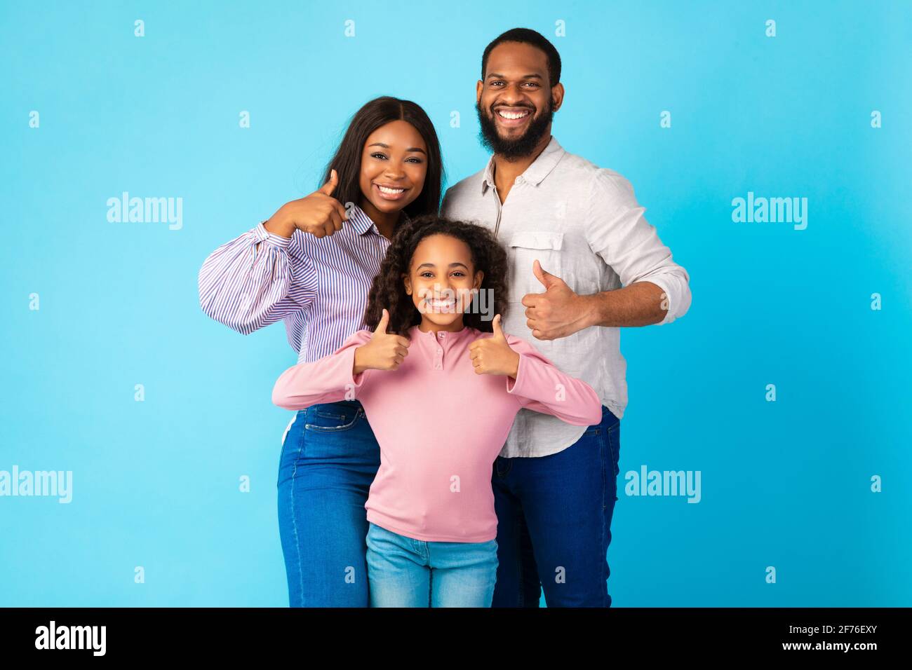 Happy black family gesturing thumbs up and smiling Stock Photo - Alamy
