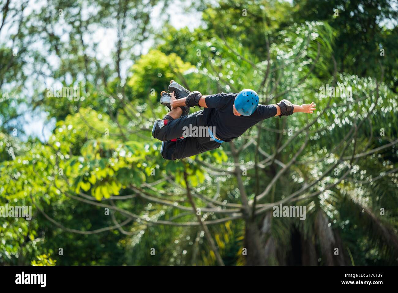 Man freestyle extreme rollerblading high in the air with inline skates and helmet at Municipal Park of Mangabeiras, Belo Horizonte, Brazil Stock Photo