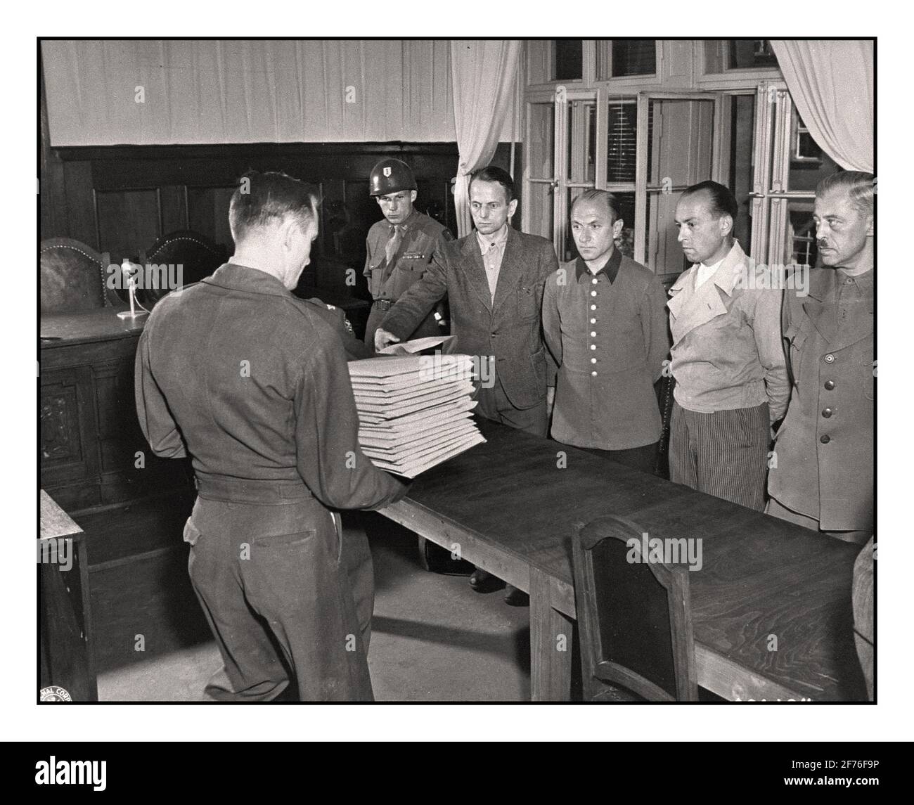 NAZI GERMANY WAR CRIMES NUREMBERG  Defendant Otto Ohlendorf (left) receives his indictment from Col. C.W. Mays, Marshal of the Military Tribunal, before the Einsatzgruppen Trial. The other defendants (left to right) are, Heinz Jost, Erich Naumann, and Erwin Schulz. Stock Photo