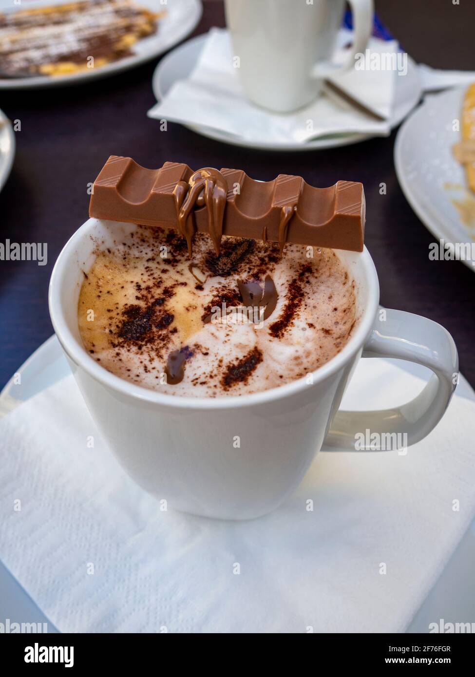 cup of cappuccino coffee with cocoa powder and a chocolate bar