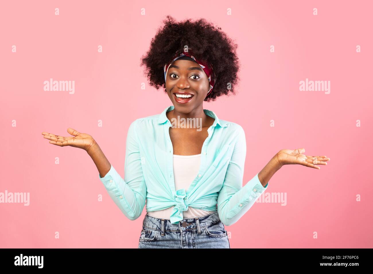Cheerful Black Woman Shrugging Shoulders Smiling To Camera, Pink Background Stock Photo