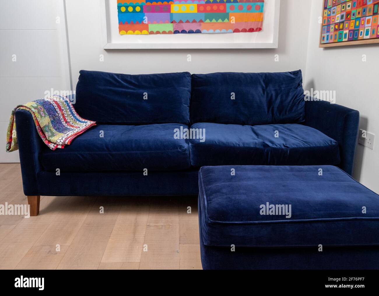 Comfortable blue velvet sofa with matching blue velvet footstool and