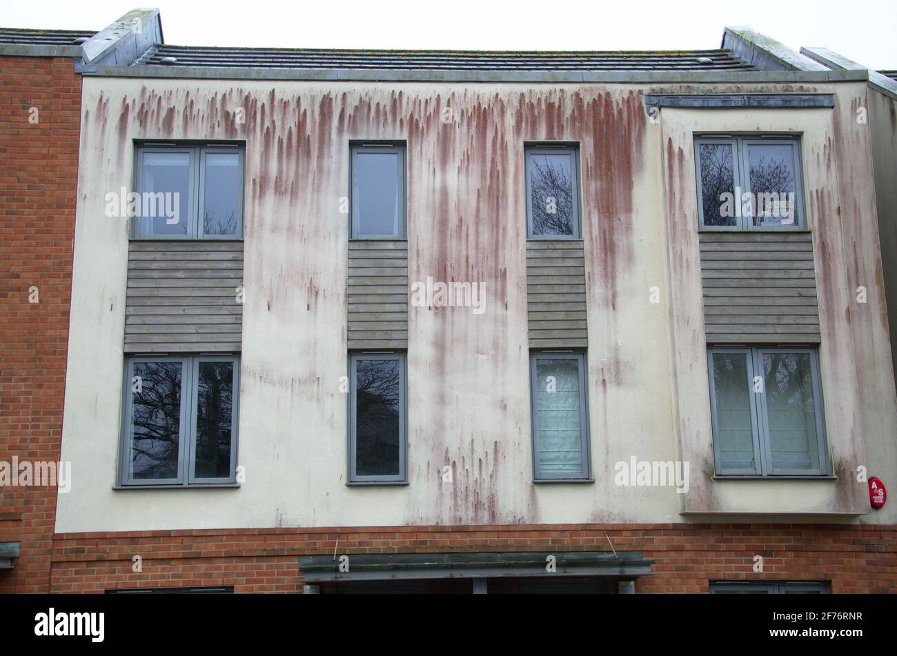 Staining on a rendered building exterior caused by red algae growth. Stock Photo