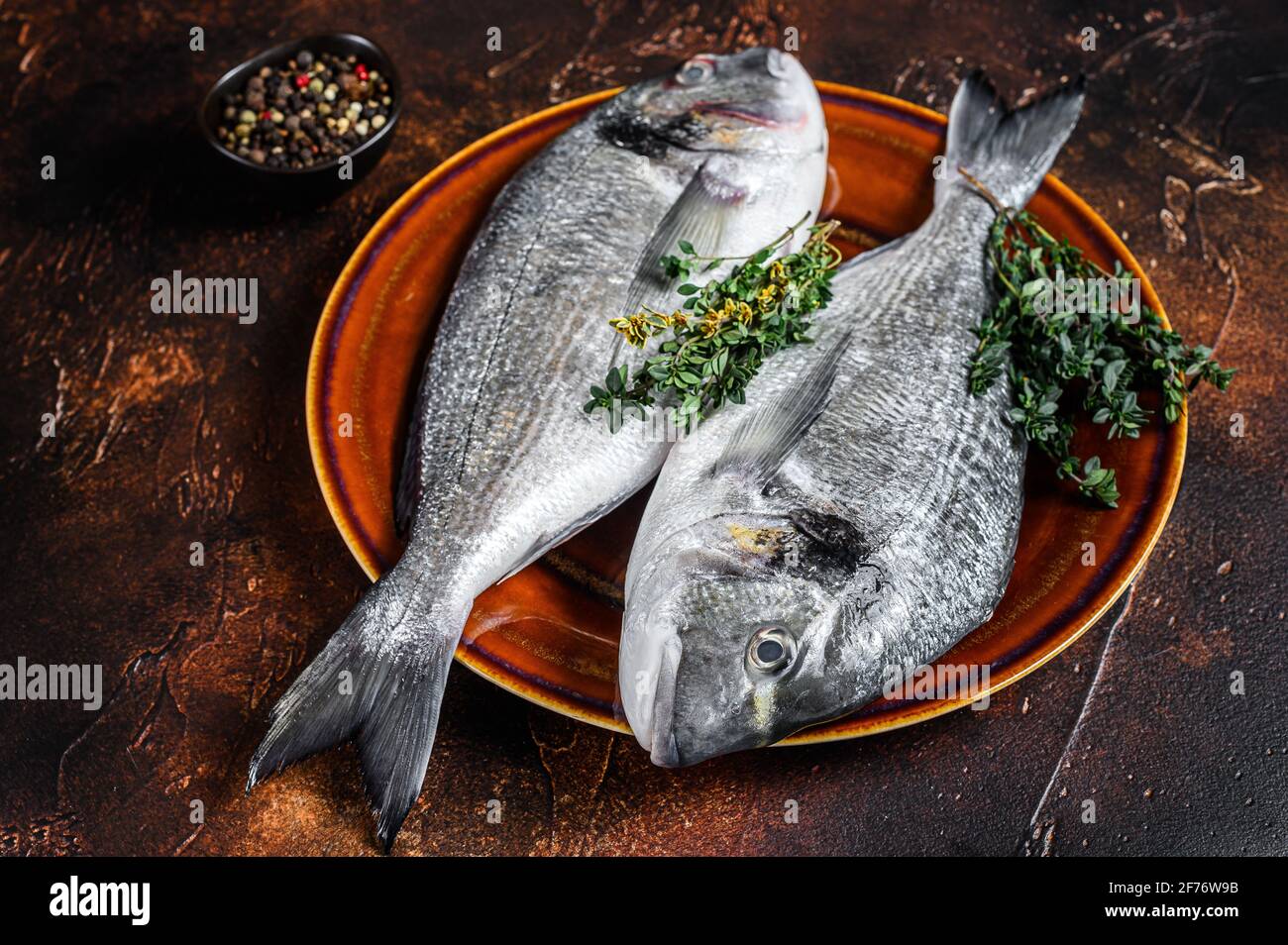 Raw Sea bream fish and ingredients for cooking. Dark background. Top ...