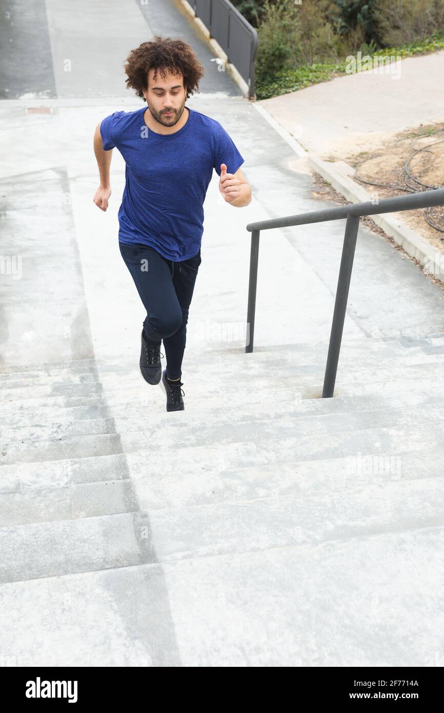 a young male athlete trains on the street by climbing stairs Stock Photo