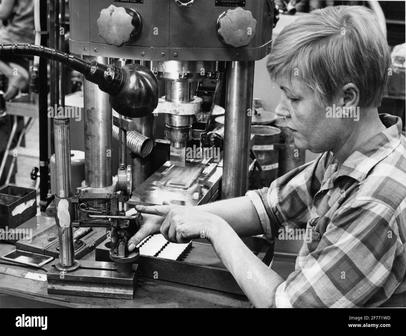Fabersta Bruks AB. Mrs. Hilkka Rool at a machine, where carbide powder is pressed for S.K. Form pieces, in this case cut to rock drills. Each molding is immediately monitored after the pressing. Stock Photo
