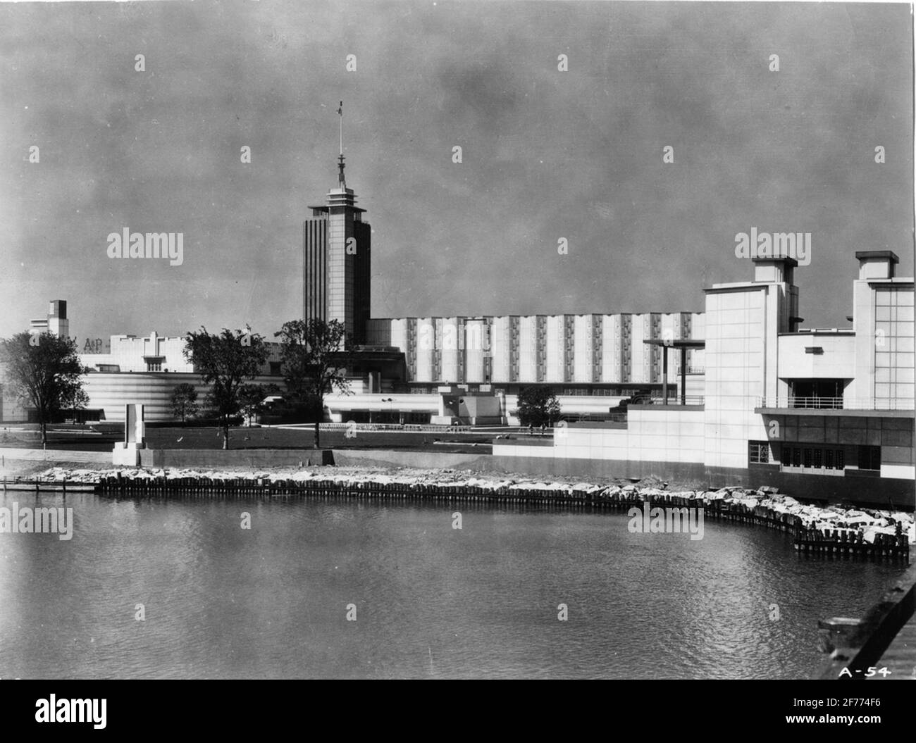 World exhibition in Chicago in 1933. The exhibition hall, where the development of modern science during a decenium was shown. This immense building, 700 x 400 feet, with the shape of a U enclosed on three sides of a farm, holding 80,000 people. In one corner a 176 foot high tower. On the front of the building a week lagoon and beyond an island and Lake Michigan. At night, a glint of the brilliant illuminated metal and glass, traveling over color shifting terraces. Stock Photo