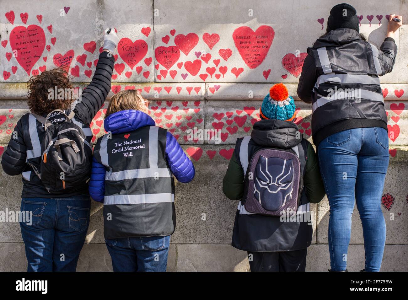 Volunteers paint red hearts on the National Covid Memorial Wall in London. The National Covid Memorial Wall in London outside St Thomas' Hospital is being hand-painted with 150000 hearts to honor UK Covid-19 victims. (Photo by Pietro Recchia / SOPA Images/Sipa USA) Stock Photo