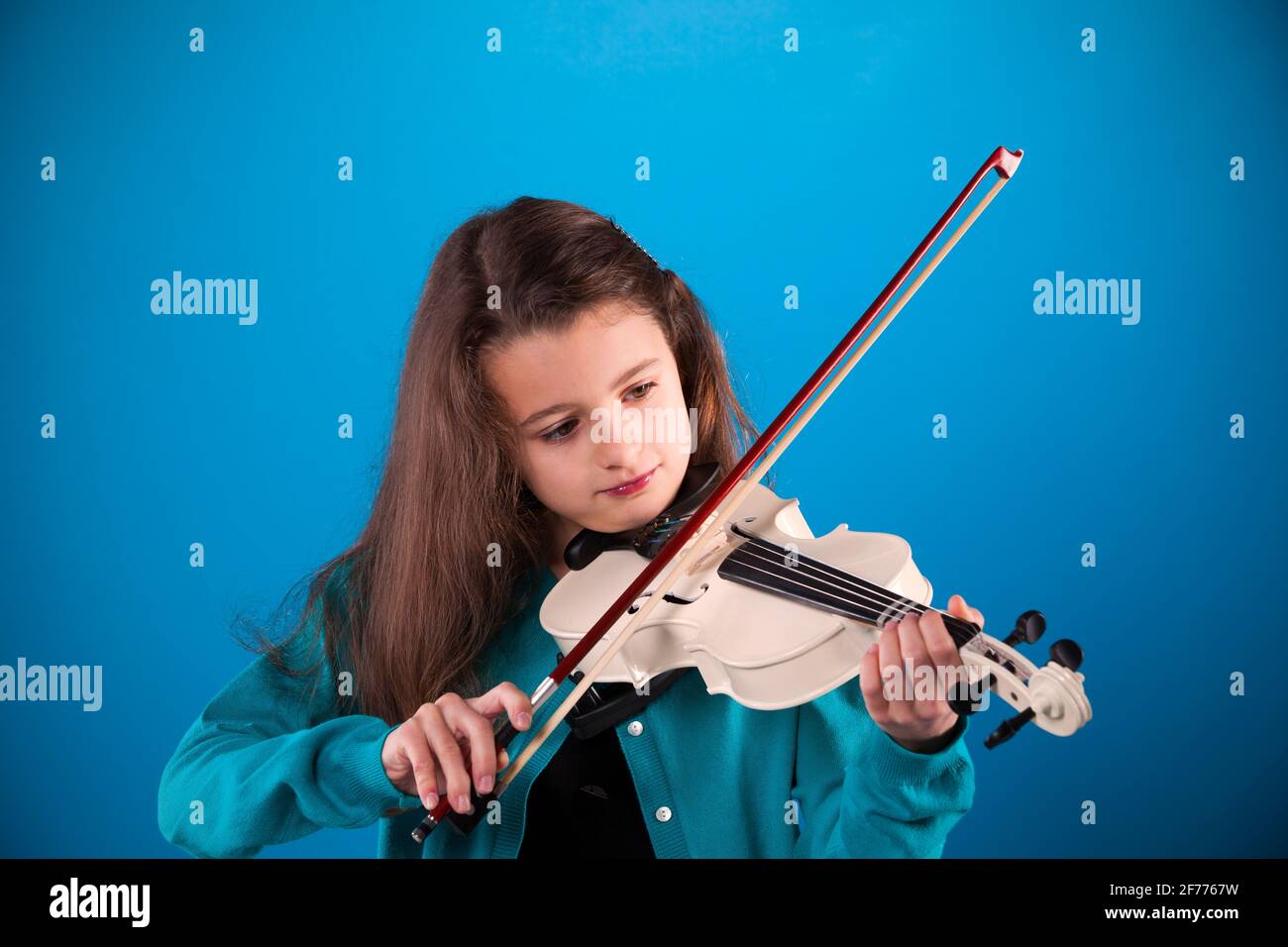 Female child playing the violin with blue background Stock Photo - Alamy