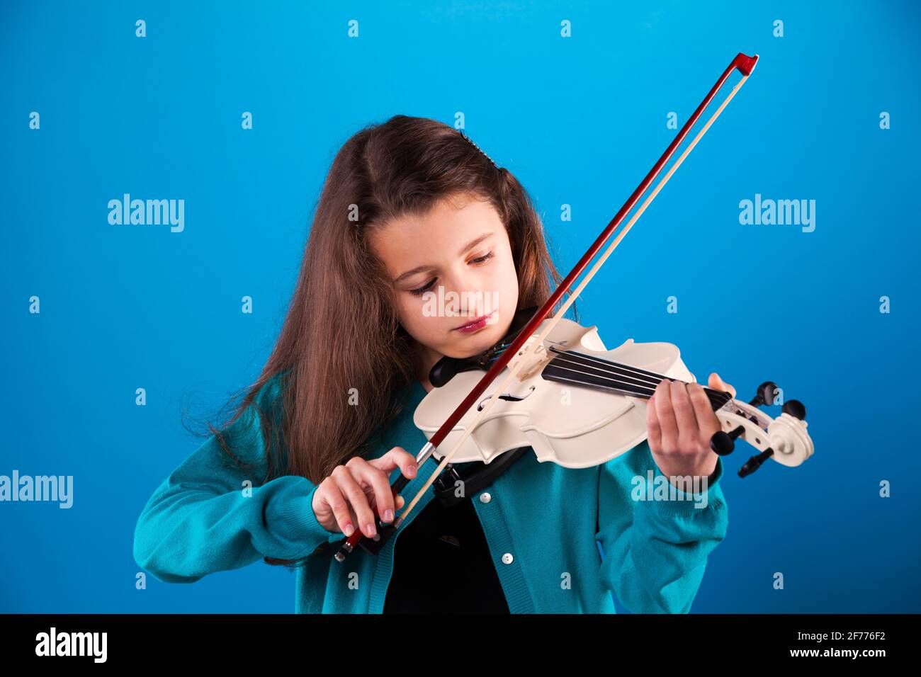 Female child playing the violin with blue background Stock Photo