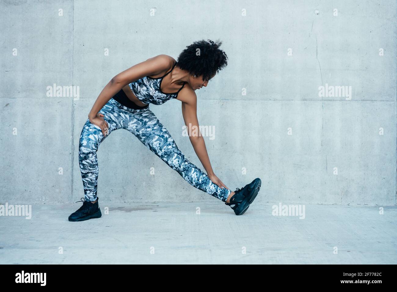 Afro athletic woman stretching legs before exercise. Stock Photo