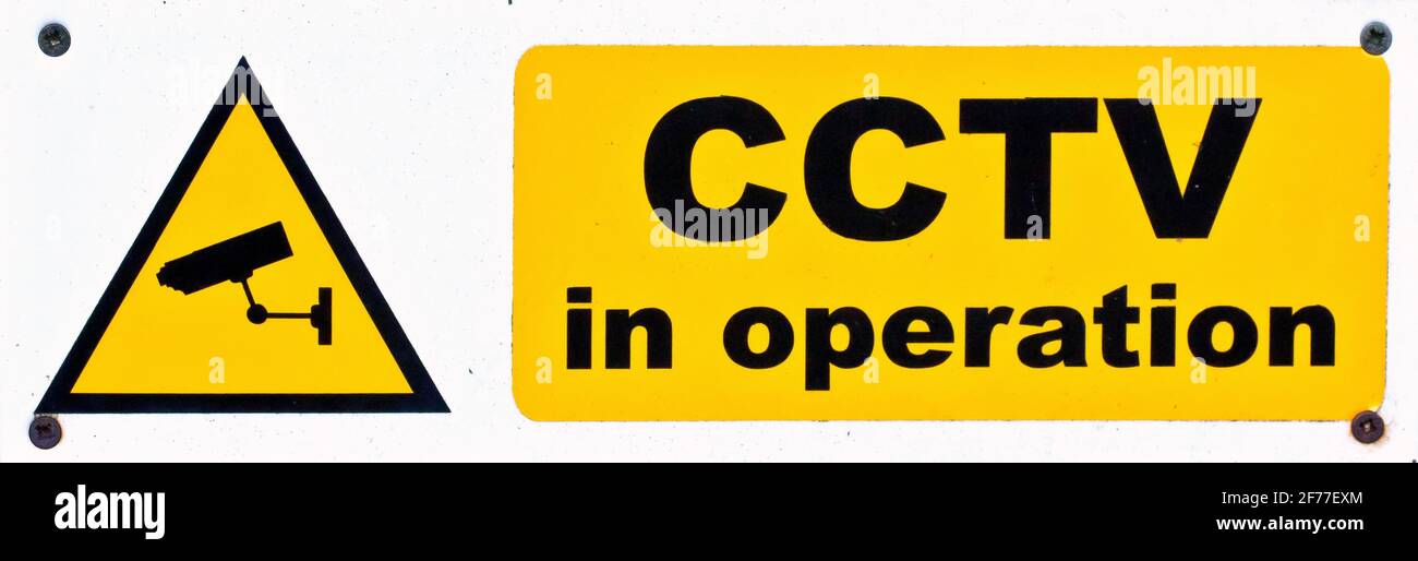 Close up cutout of warning sign indicating CCTV is in operation, black lettering on a yellow base. Stock Photo