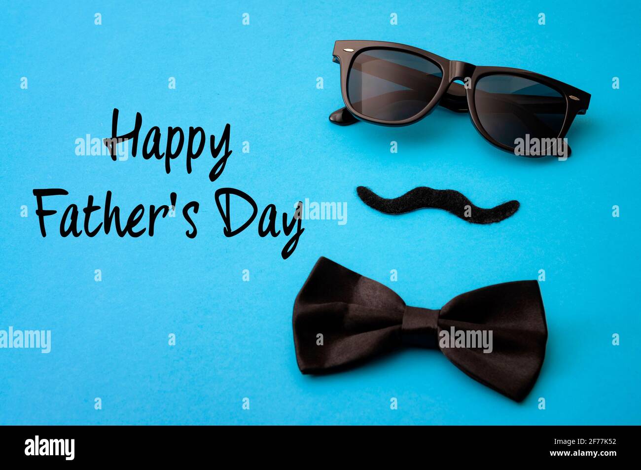 Father day and male hipster fashion concept with minimalist image of a pair of square sunglasses, black bowtie and a fake moustache on colorful blue b Stock Photo