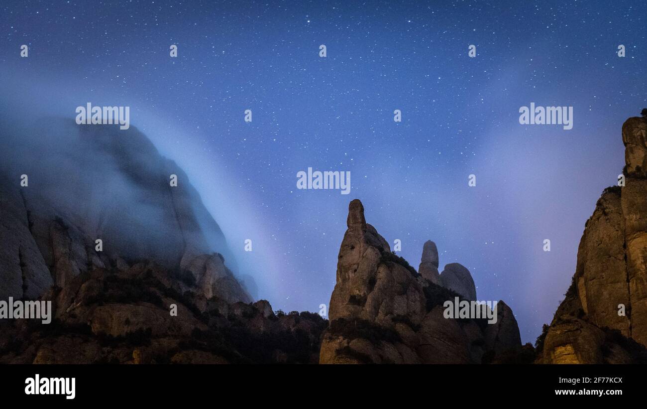Night fogs behind the silhouette of Talaia and Sant Jeroni spires, in Montserrat (Barcelona province, Catalonia, Spain) Stock Photo