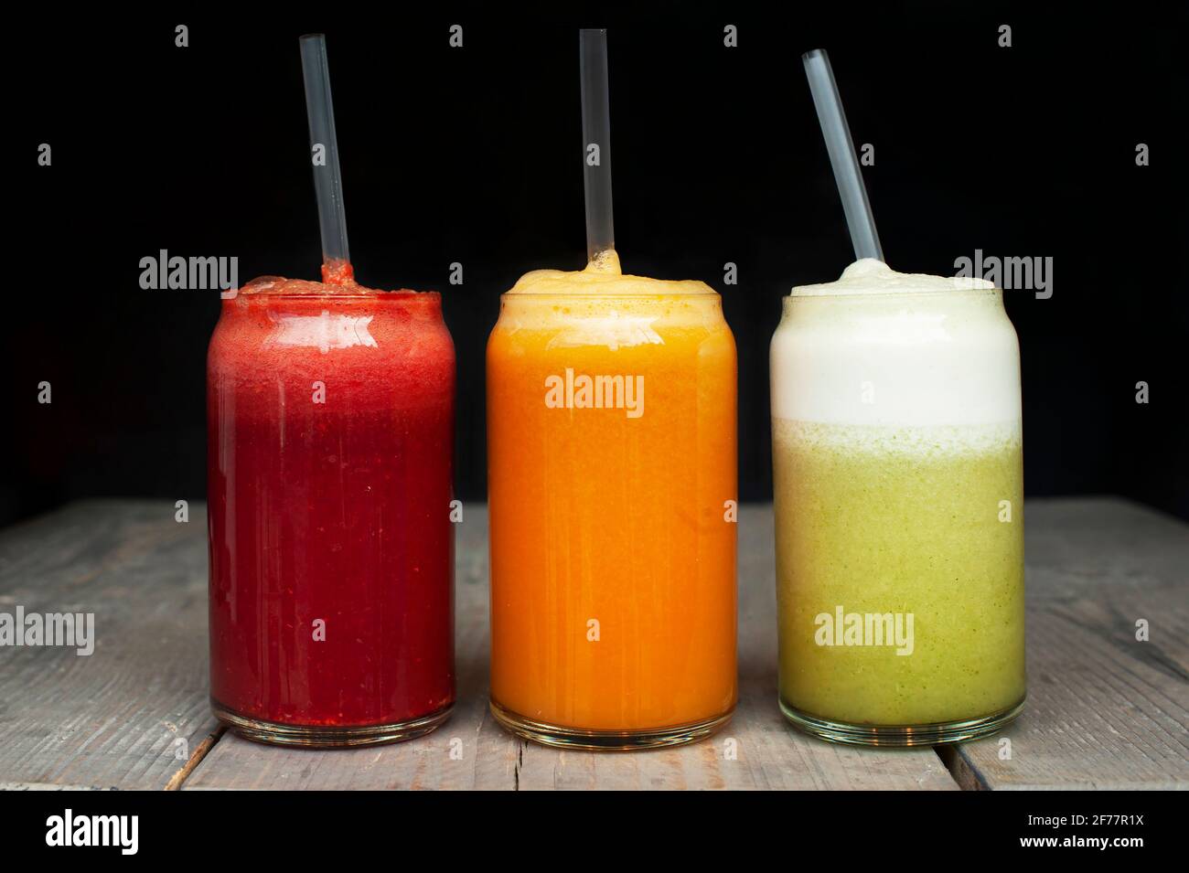 Three glasses of colourful fresh juices with plastic straws. Beet, orange and green juice diet concept Stock Photo